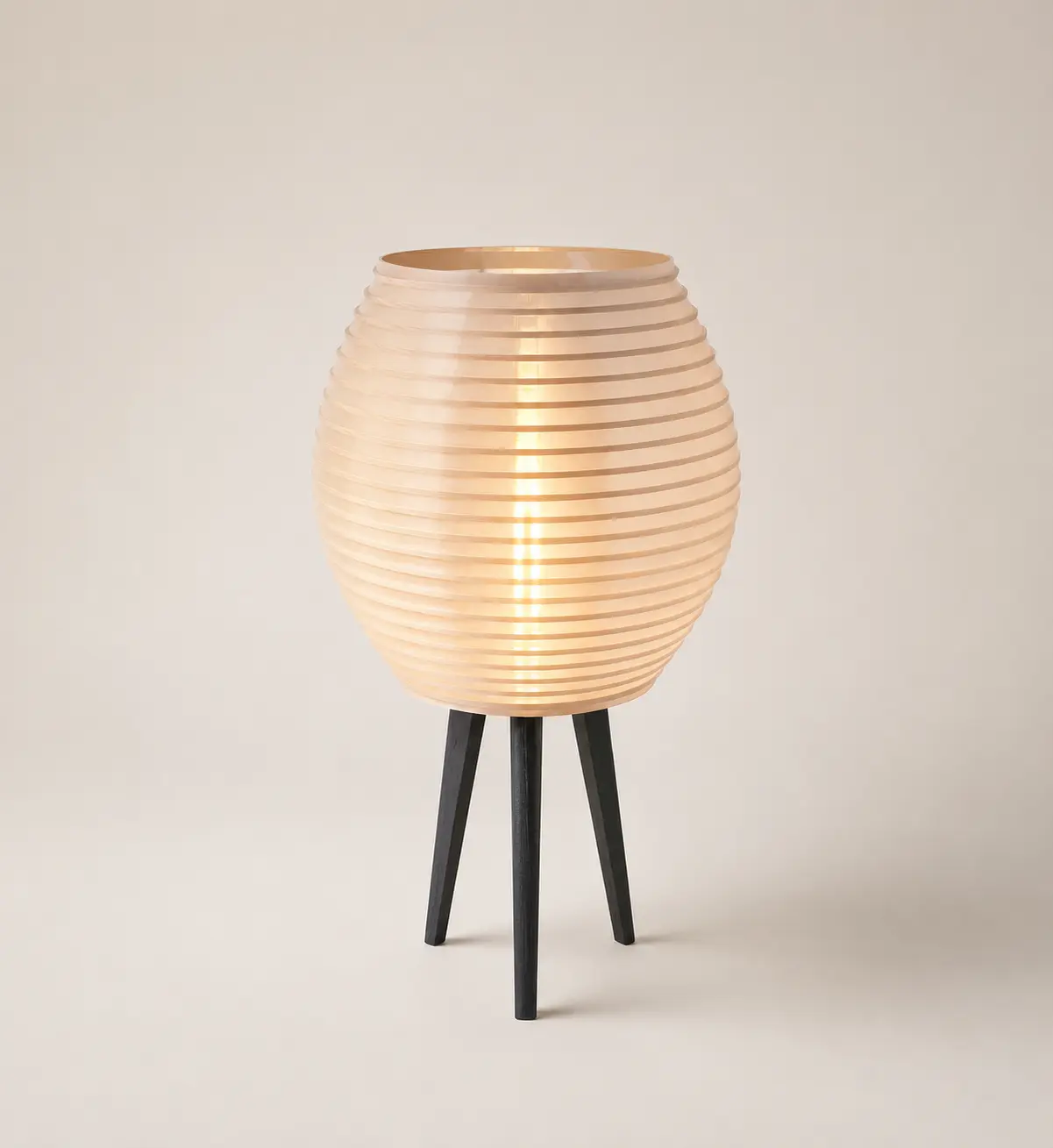 Ember lamp by Bunk Studios - a honey-toned ribbed pod glowing on three dark legs